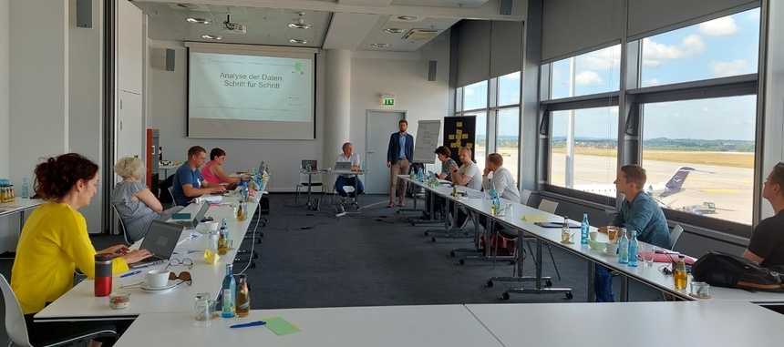 Tisch in U-Form mit Personen die nach vorn zum Referenten schauen,