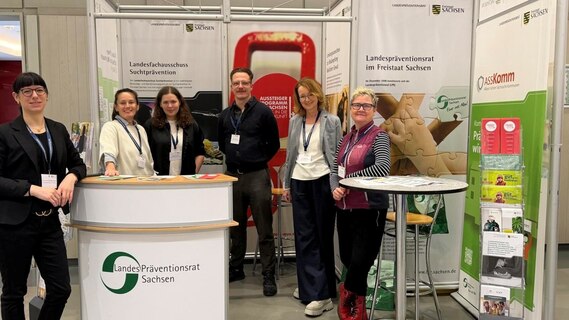sechs Personen, fünf Frauen und ein Mann, stehen vor einem Messestand und lächeln.