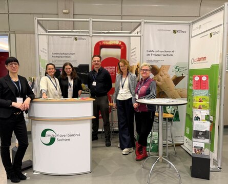 sechs Personen, fünf Frauen und ein Mann, stehen vor einem Messestand und lächeln.