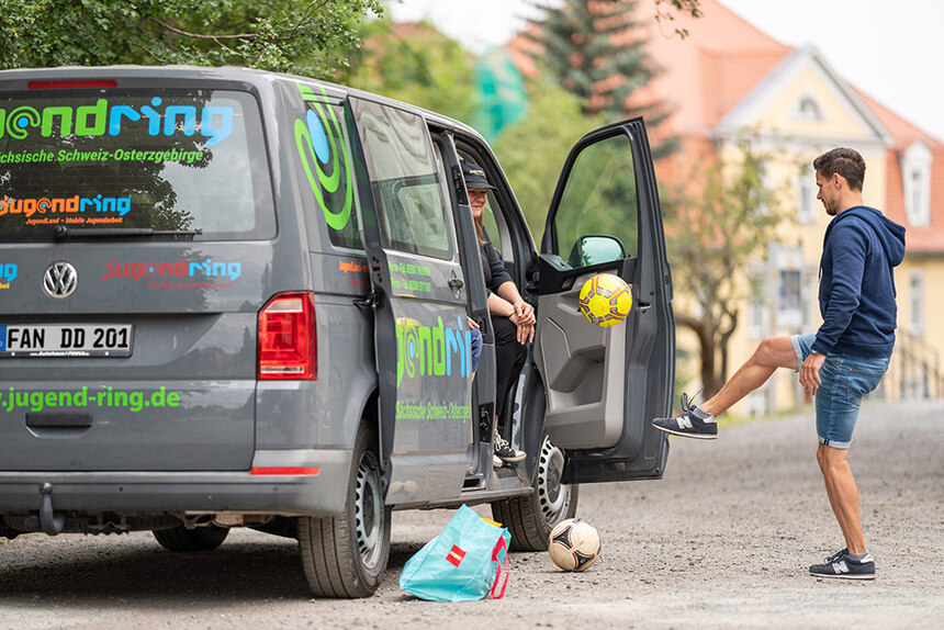 Kleintransporter mit zwei jungen Menschen, die mit dem Ball jonglieren