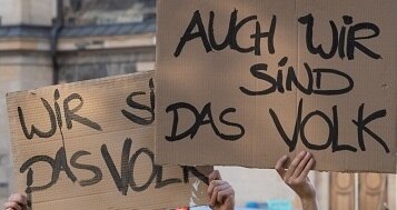 eine Gruppe junger Menschen halten beschriebene Pappen "Wir sind auch das Volk" hoch, dabei sind sie als Hummeln verkleidet