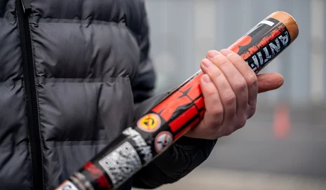 der Brustbereich von einer Person mit Jacke hält einen Baseballschläger