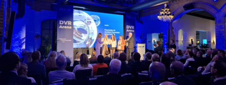 Viele Menschen sitzen auf Stühlen und schauen zu einer Bühne auf der mehrere Menschen stehen, denen ein Preis der Vision Zero Award ausgehändigt wird.