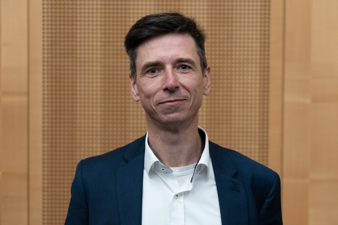 Portrait von Matthias Böhme vor einer hellbraunen Holzwand