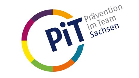 PIT, weißer Untergrund mit buntem Kreis darin steht PiT und rechts daneben Präention im Team Sachsen