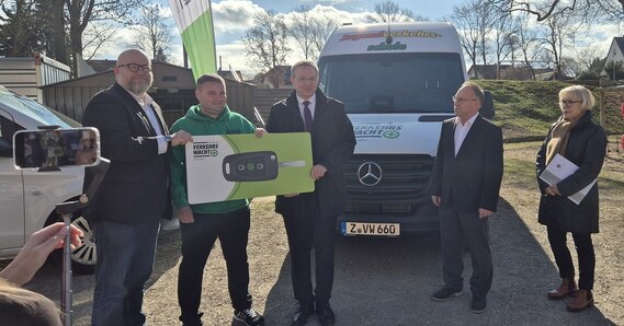 Personen die symbolisch einen Autoschlüssel in der Hand halten und in die Kamera lächeln