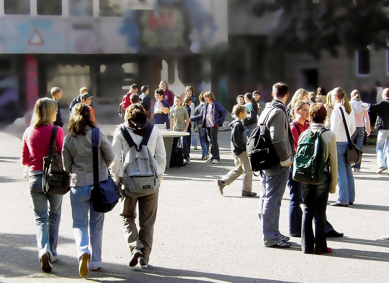 Viele Jugendliche auf einem Schulhof in verschiedenen Darstellungen, in Gruppen stehend, laufend oder stehend.