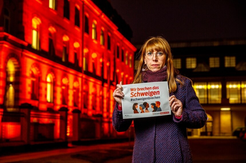 Bild zeigt Staatministerin für Gleichstellung und Justiz Katja Meier vor dem orange angestrahlten Gebäude des Justiz- und Gleichstellungsministeriums am "World Orange Day" 2021