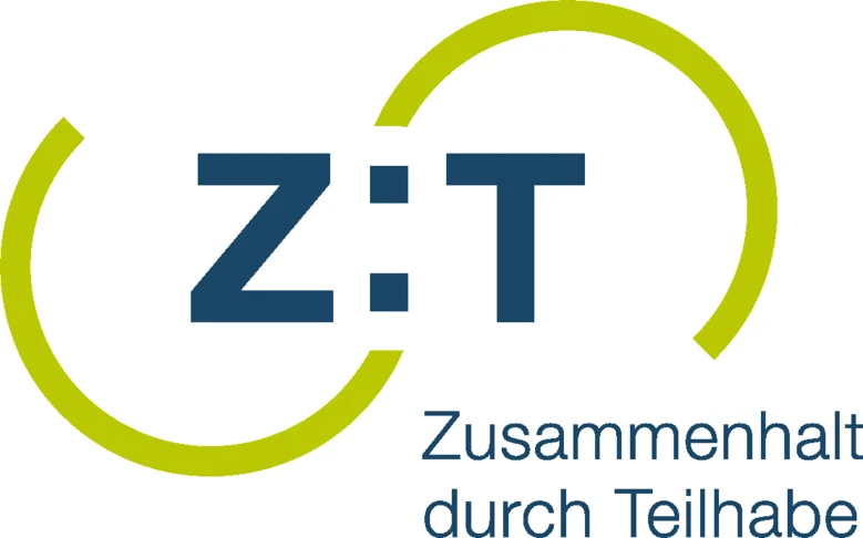 Das Logo des Bundesprogrammes »Zusammenhalt durch Teilhabe« zusammengesetzt aus den Großbuchstaben »Z« und »T«, getrennt durch einen Doppelpunkt. Die Buchstaben sind durch jeweils einen nach unten und oben geöffneten, hellgrünen Halbkreis eingerahmt.